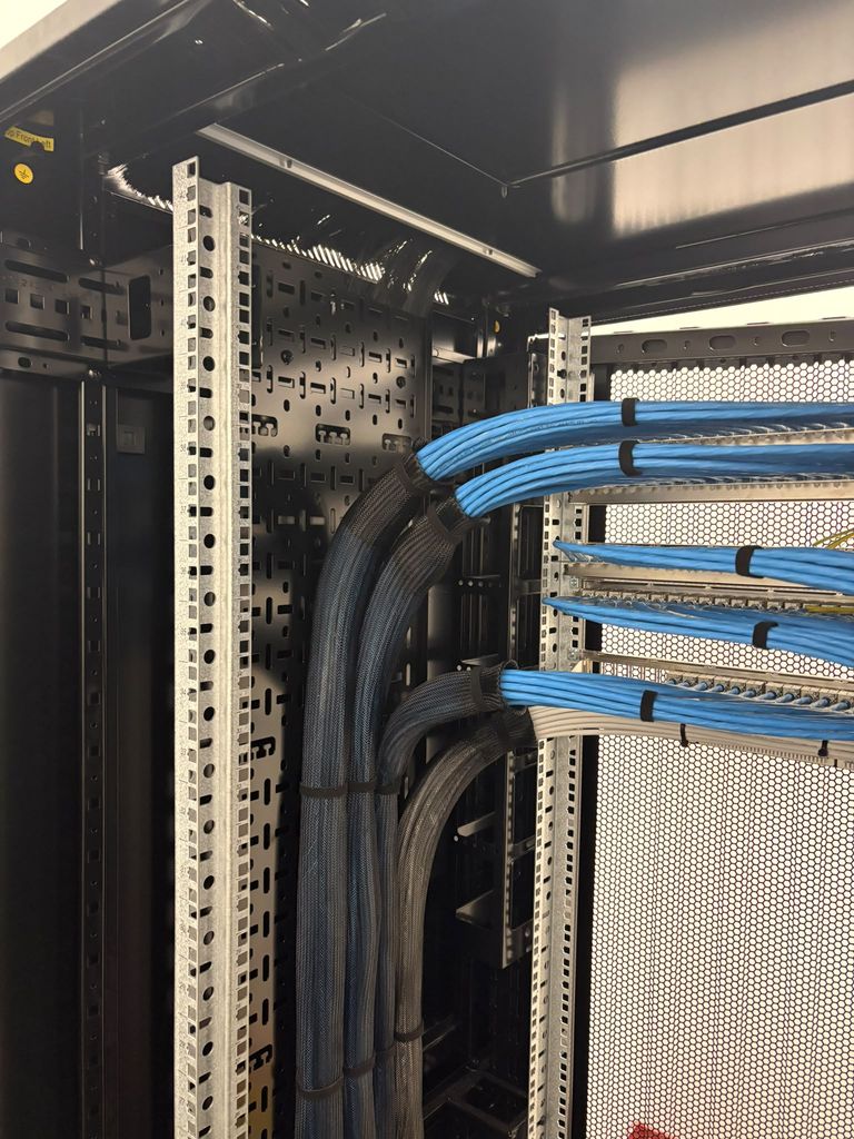New cabinet build with blue Cat6 looms swept from the sleeved risers into the panels